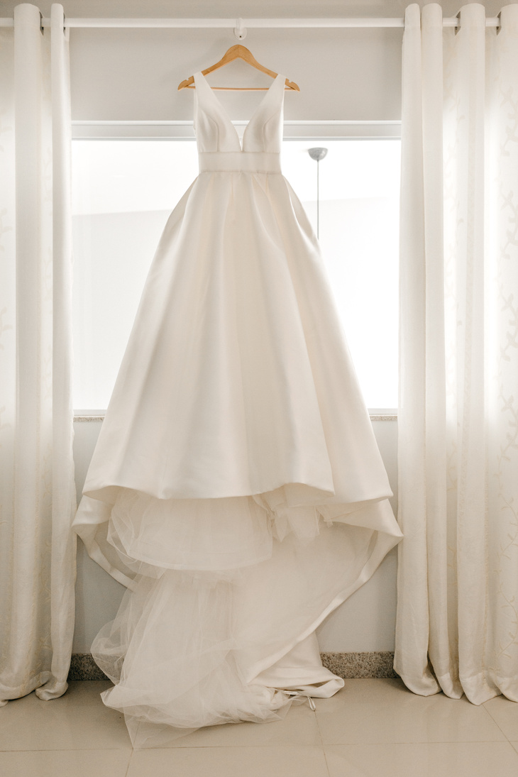 White wedding dress on hanger near window